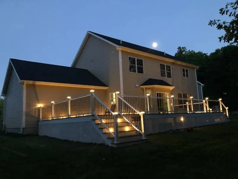 Elevated deck with warm lighting illuminating the house at dusk