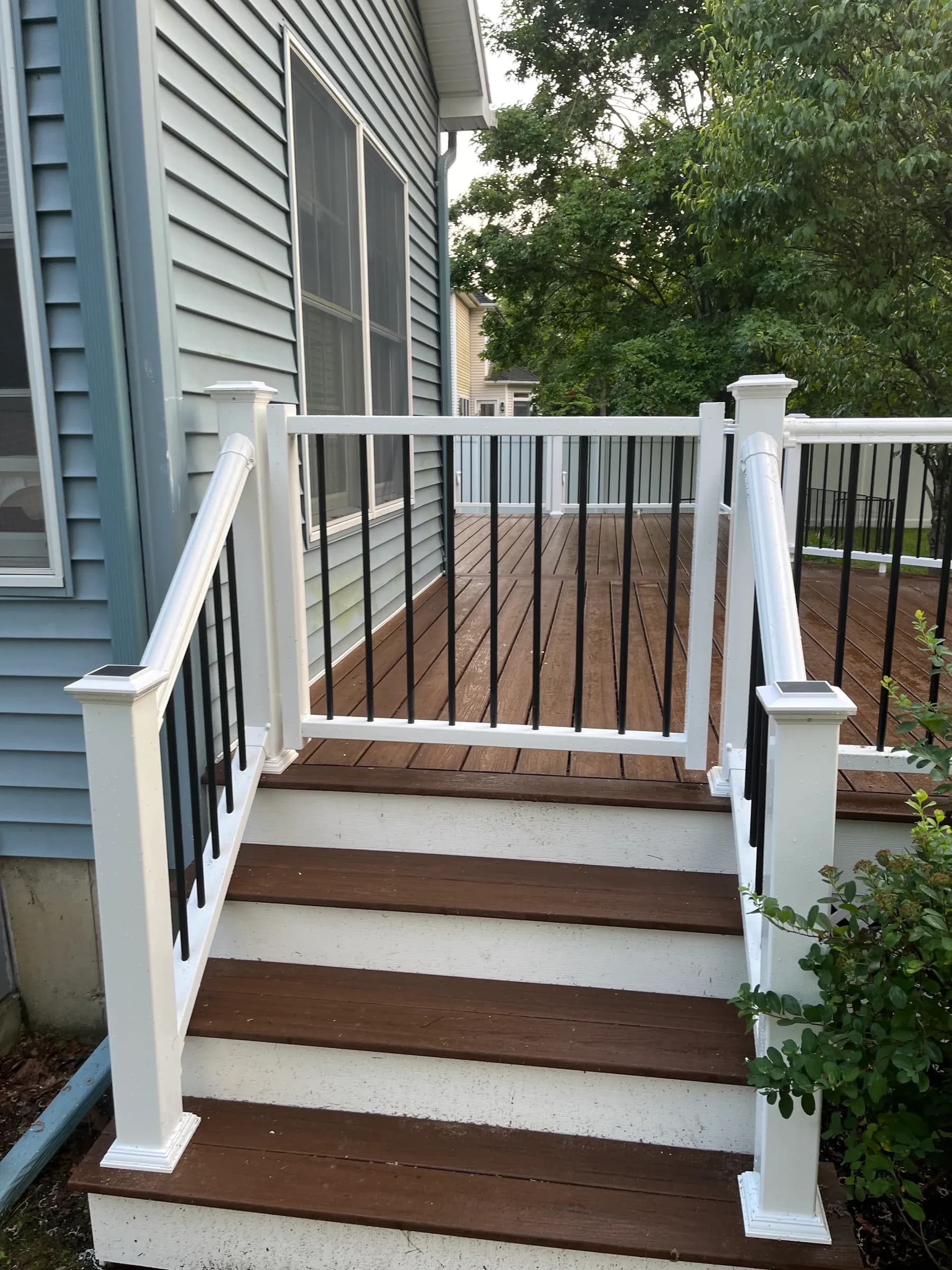 Deck with modern white cable railing and brown fence