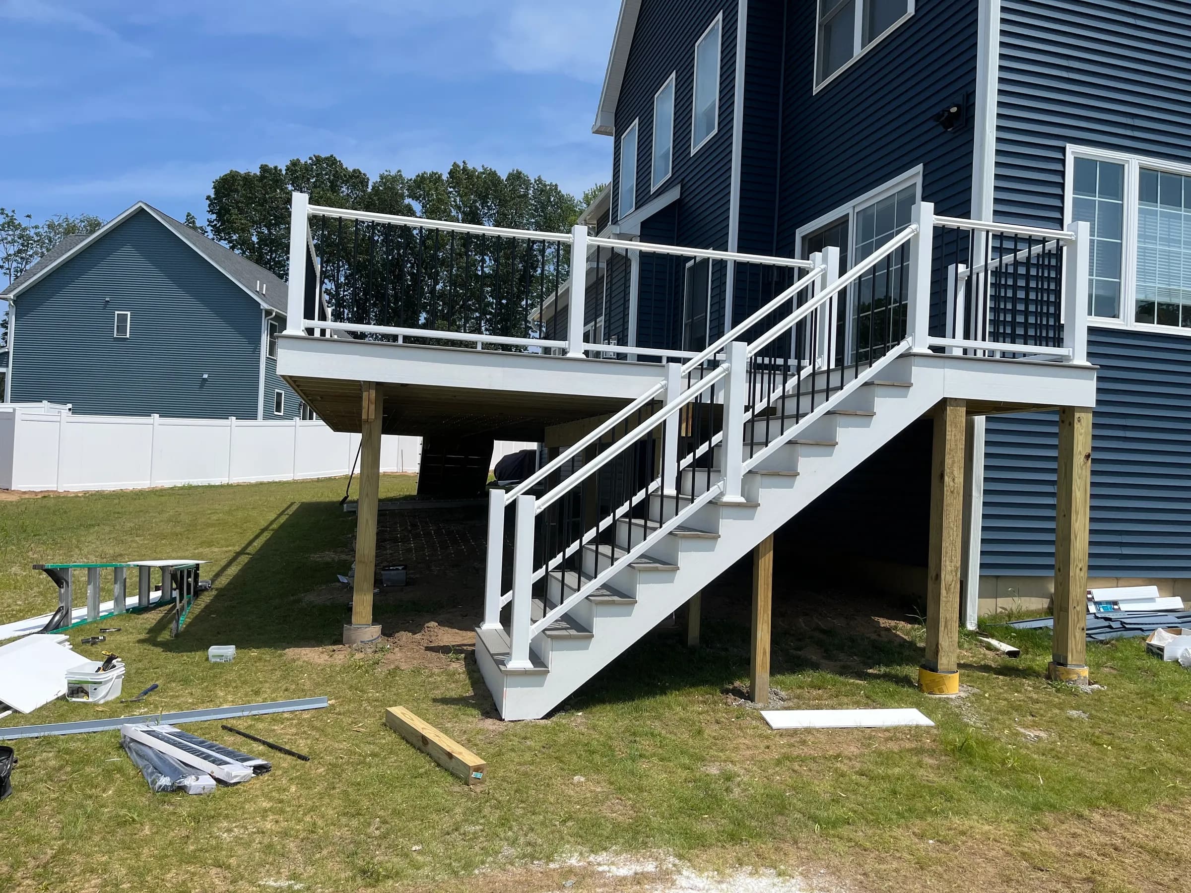 White deck with long staircase to yard on navy blue home